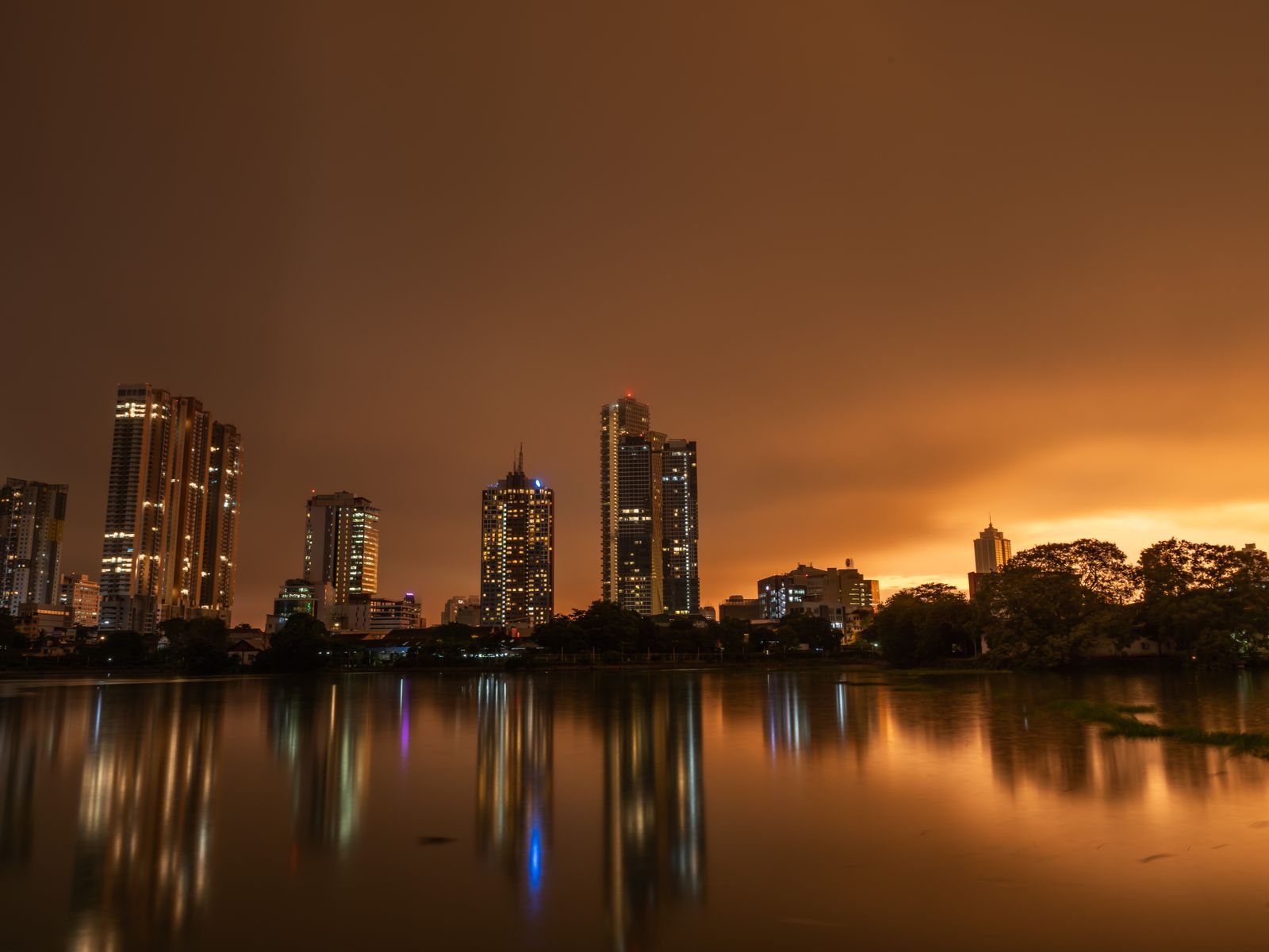 Sri Lankan city skyline reflected in a lake at twilight.