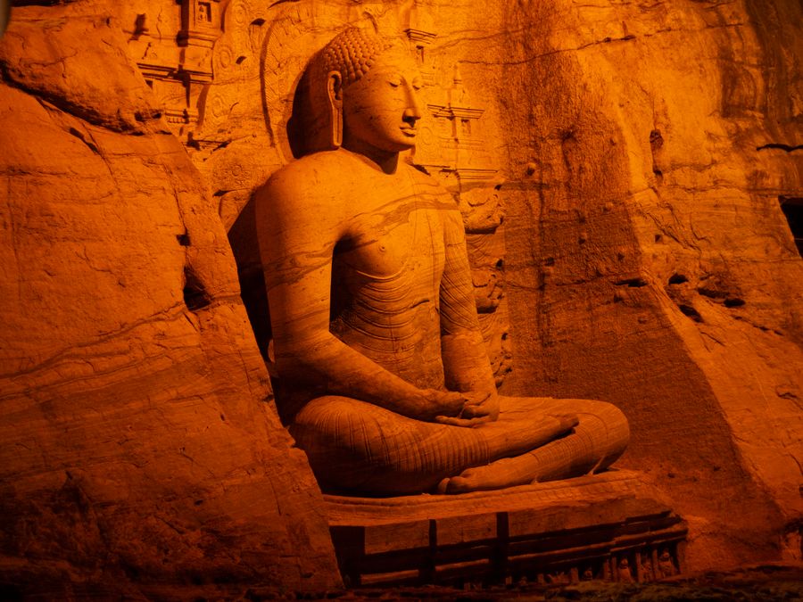 Colossal Buddha figures carved into a granite rock face at Polonnaruwa