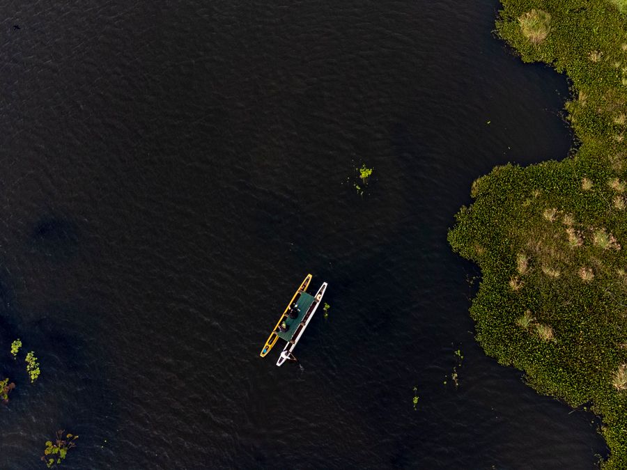 A wooden canoe on the still water of a lake at Habarana, framed by trees