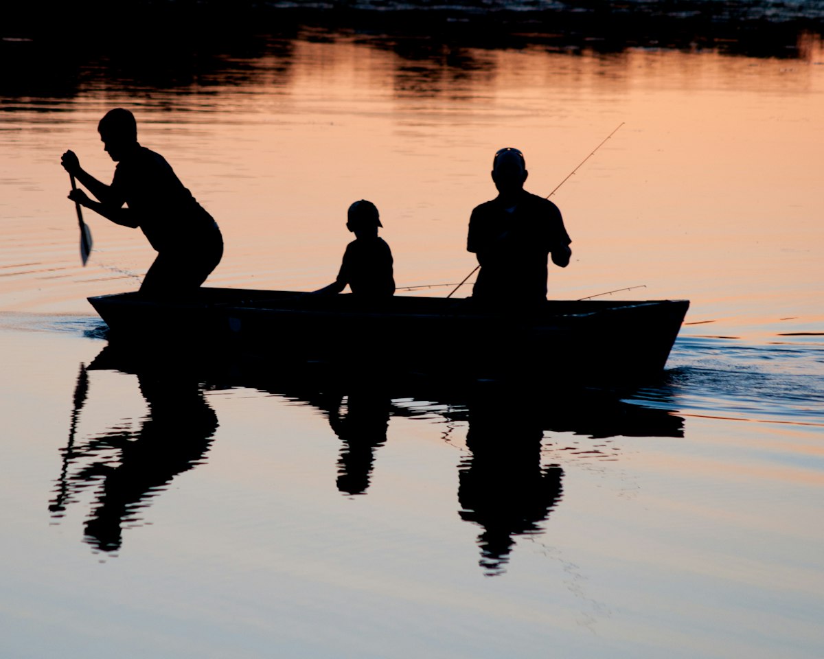Traditional stilt fishermen perched on poles in the sea at sunset on Sri Lanka's south coast